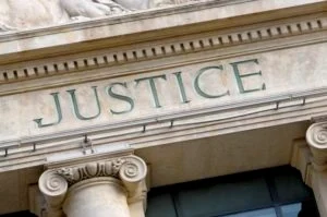 Stone facade of a courthouse with the word JUSTICE engraved above large classical columns
