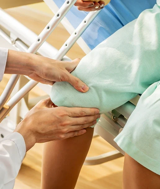 Doctor examining a patient's knee while the patient holds crutches, focusing on knee care and mobility support